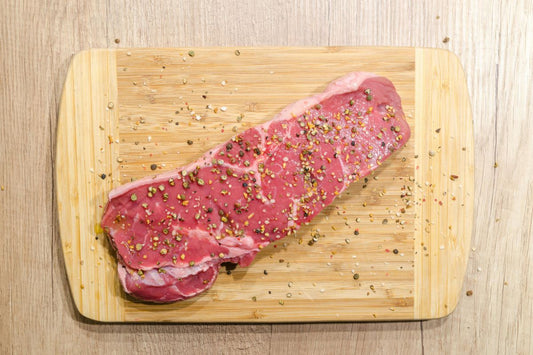 A piece of raw meat on a wooden board